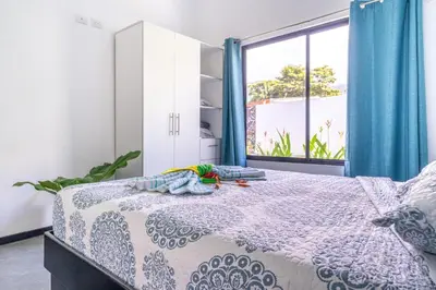 a bedroom with a bed with blue curtains and a window at Uvita-Great location-3 bedroom-Private pool-Gated in Uvita