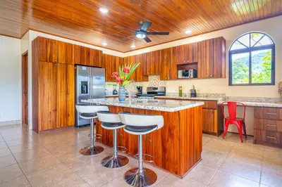 a kitchen with wooden cabinets and a bar with stools at 4 bedroom-sleep 9-private pool-gated-Ojochal in Ojochal
