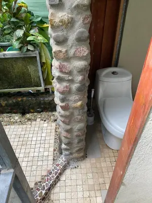 a stone pillar in a bathroom with a toilet at Casa Mariposa, Playa Ostional in Nosara