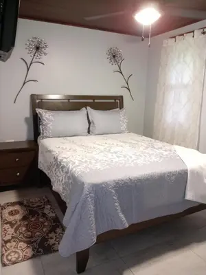 a bedroom with a bed with white sheets and flowers on the wall at Magnolia Farm Suites in San Isidro