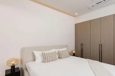 a white bedroom with a large white bed with two pillows at Cielo de Coco at Naumi, Ocean Views & Beach Club in Sardinal