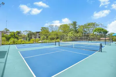 a tennis court with two tennis courts at Brisa del Valle at Naumi, Ocean Views & Beach Club in Sardinal