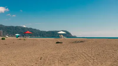 a sandy beach with umbrellas and chairs and the ocean at Luxury Walkout Beachfront Jaco Condo-Sleep 6 in Jacó