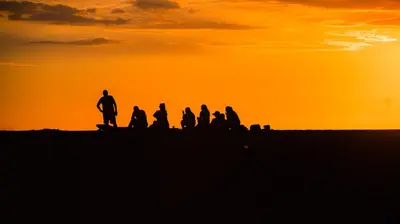a group of people sitting on a hill at sunset at Luxury Walkout Beachfront Jaco Condo-Sleep 6 in Jacó