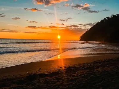 a sunset on a beach with the ocean at Luxury Walkout Beachfront Jaco Condo-Sleep 6 in Jacó