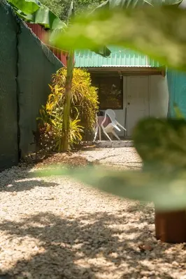 a building with a door and a chair in a yard at Quiet cabin 10 minutes from the sea in Nicoya