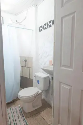 a white bathroom with a toilet and a sink at Quiet cabin 10 minutes from the sea in Nicoya
