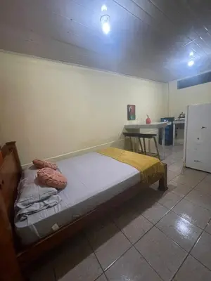 a bedroom with a bed and a table in it at Quiet cabin 10 minutes from the sea in Nicoya
