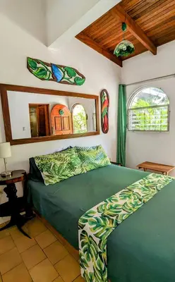 a bedroom with a green bed and two windows at Tico Tiki Vacation Villa - Epic View & Pool, 5 Minute walk to beach! in Sámara