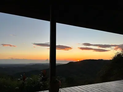 a view of the sunset from a house window at Villa Arcoiris in San Ramón