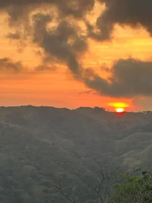 a sunset with the sun setting over the mountains at Villa Arcoiris in San Ramón