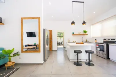 a kitchen with a counter and two stools in it at CasaBlanca with Pool, 5 min from the Ocean in Cuajiniquil