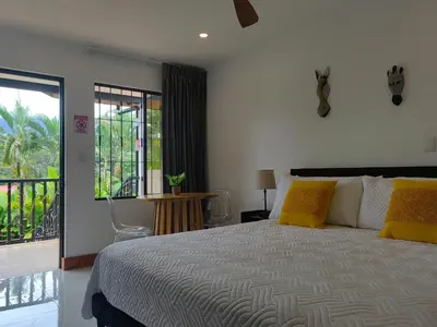 a bedroom with a large bed and a balcony at Arenal Palms Hot Springs in Chachagua