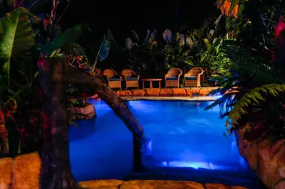 a resort swimming pool with chairs and plants at Arenal Palms Hot Springs in Chachagua