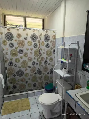 a bathroom with a shower curtain and a toilet at Pacayitas El Camino House in Turrialba
