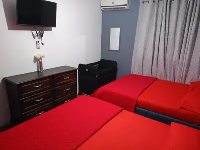 a bedroom with two beds and a dresser with red sheets at Harmony Retreat in Fortuna