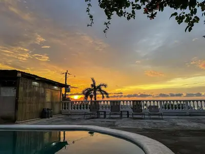 a pool with benches and a sunset in the background at Apt 33 Best Ocean Views Hilltop Oasis in Tamarindo