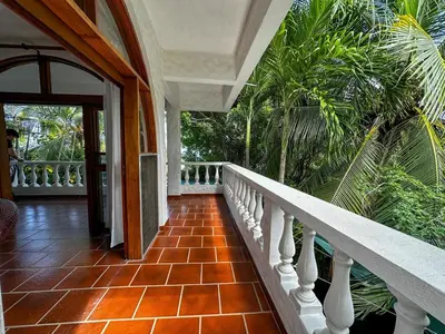 a balcony of a house with a staircase and palm trees at Apt 47 Hilltop Retreat Ocean Garden Views in Tamarindo