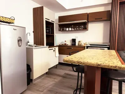 a kitchen with a refrigerator and a table with stools at Stunning Sunset View Apartment with Free Parking in San José