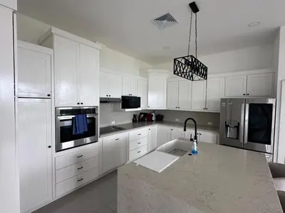 a white kitchen with white cabinets and a sink at Luxury 4BR home with Infinity Pool & firepit in Playa Hermosa