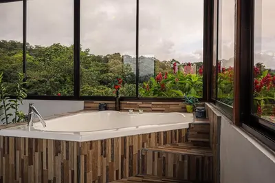 a large bath tub in a bathroom with windows at Volcano & Lake View Oasis with Scenic Tub in El Castillo de La Fortuna