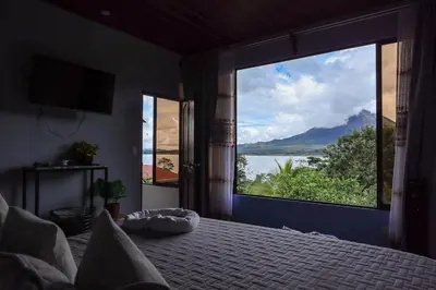 a bedroom with a large window with a view of the water at Volcano & Lake View Oasis with Scenic Tub in El Castillo de La Fortuna