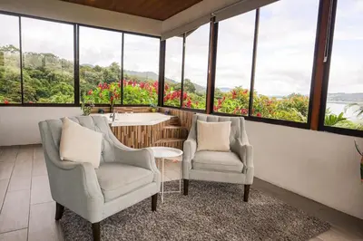 two chairs and a sink in a room with windows at Volcano & Lake View Oasis with Scenic Tub in El Castillo de La Fortuna