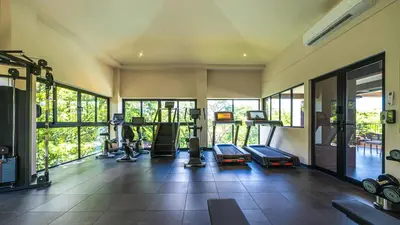 a gym with cardio equipment in a room with windows at Loma Mar at Naumi, Ocean Views & Beach Club in Sardinal