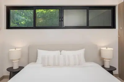 a bedroom with a white bed and two windows at Loma Mar at Naumi, Ocean Views & Beach Club in Sardinal