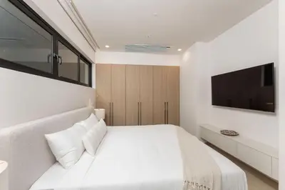 a bedroom with a white bed and a tv at Loma Mar at Naumi, Ocean Views & Beach Club in Sardinal