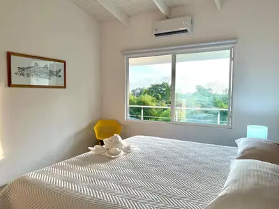 a white bedroom with a bed and a window at Casa Blanca Manuel Antonio B2, Central, Pool, Gated in Manuel Antonio