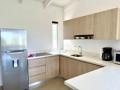 a kitchen with a stainless steel refrigerator and wooden cabinets at Casa Blanca Manuel Antonio B2, Central, Pool, Gated in Manuel Antonio