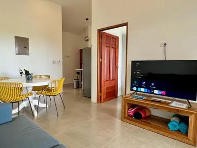 a living room with a tv and a table with chairs at Casa Blanca Manuel Antonio A3 in Manuel Antonio