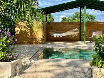 a hammock in a backyard with a swimming pool at Casa Blanca Manuel Antonio A3 in Manuel Antonio