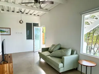 a living room with a green couch and a tv at Casa Blanca Manuel Antonio A2, Central, Pool, Gated in Manuel Antonio