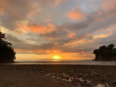 a sunset on a beach with the sun setting at Jaguar, 2 BR Penthouse in Villa Mar y Sol, Nature and Wildlife in Manuel Antonio