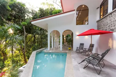 a house with a swimming pool and a red umbrella at Villa Lapas, Central, Spacious and Lots of Wildlife in Manuel Antonio