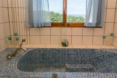 a bathroom with a blue tiled tub with a window at Castillo de Amber, 4 Aparts, 6 Bedrooms, Ocean Views, Central Location in Manuel Antonio
