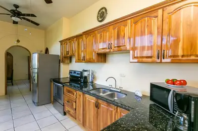 a kitchen with wooden cabinets and a stainless steel refrigerator at Castillo de Amber, 4 Aparts, 6 Bedrooms, Ocean Views, Central Location in Manuel Antonio