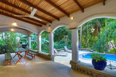 an outdoor patio with a table and a swimming pool at Villa Monos, 2BR Home, 1BR Guest House and Pool in Manuel Antonio