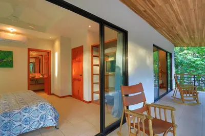 a bedroom with a bed and chairs in a room at Villa Monos, 2BR Home, 1BR Guest House and Pool in Manuel Antonio