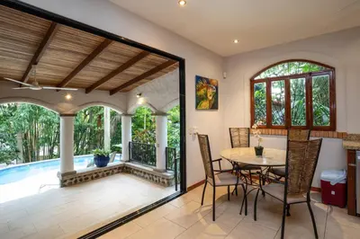 an open living room with a table and chairs and a pool at Villa Monos, 2BR Home, 1BR Guest House and Pool in Manuel Antonio