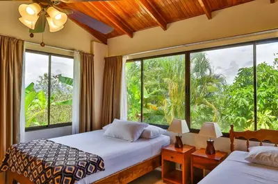 a bedroom with two beds and a large window at Casa Kilimanjaro Nature, Amazing Views and 6 Acres in Manuel Antonio