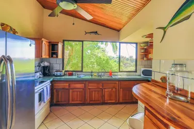 a kitchen with wooden cabinets and a large window at Casa Kilimanjaro Nature, Amazing Views and 6 Acres in Manuel Antonio