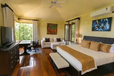 a bedroom with a large bed and a living room at Villa Vigia, beach views, 3 acres of privacy and tons of wildlife in Manuel Antonio