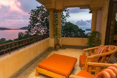 a balcony with a table and chairs and a view of the ocean at Villa Vigia, beach views, 3 acres of privacy and tons of wildlife in Manuel Antonio