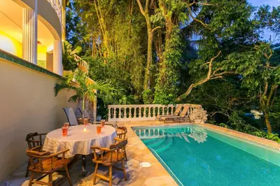 a patio with a table and chairs next to a pool at El Titi, 1 Bedroom Ocean View Apartment, Central Location in Manuel Antonio