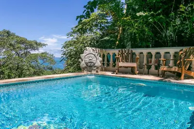 a swimming pool with two chairs and a lion statue at El Congo, 2BR Apartment w Great Ocean Views and Central Location in Manuel Antonio