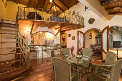 a living room with a staircase and a table and chairs at El Congo, 2BR Apartment w Great Ocean Views and Central Location in Manuel Antonio
