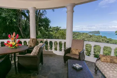 a porch with a table and chairs and the ocean at El Capuchin, 2BR Ocean View Apartment, Central Location in Manuel Antonio